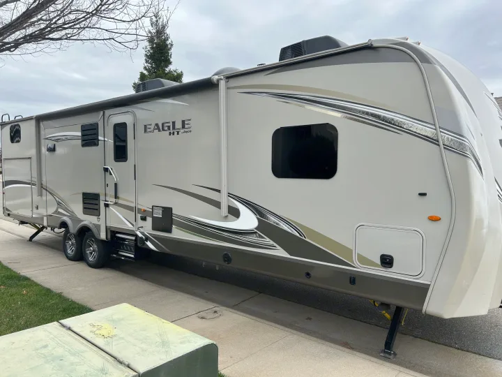 This Jayco Eagle HT travel trailer makes a great rv rental for your next outdoor adventure, parked on pavement with grass nearby.. Jayco Eagle HT 2018