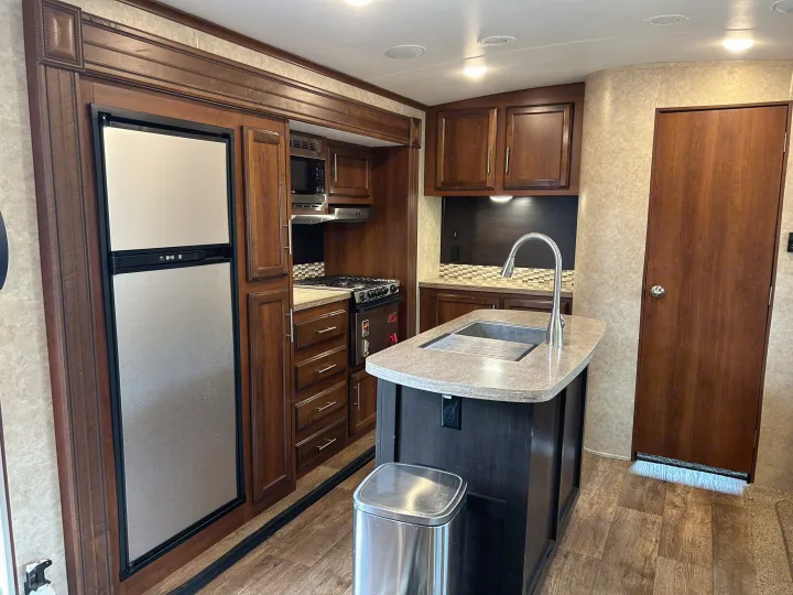 This spacious and modern RV kitchen, available for rv rental, includes a refrigerator, microwave, stove, and island.. Jayco Eagle HT 2018