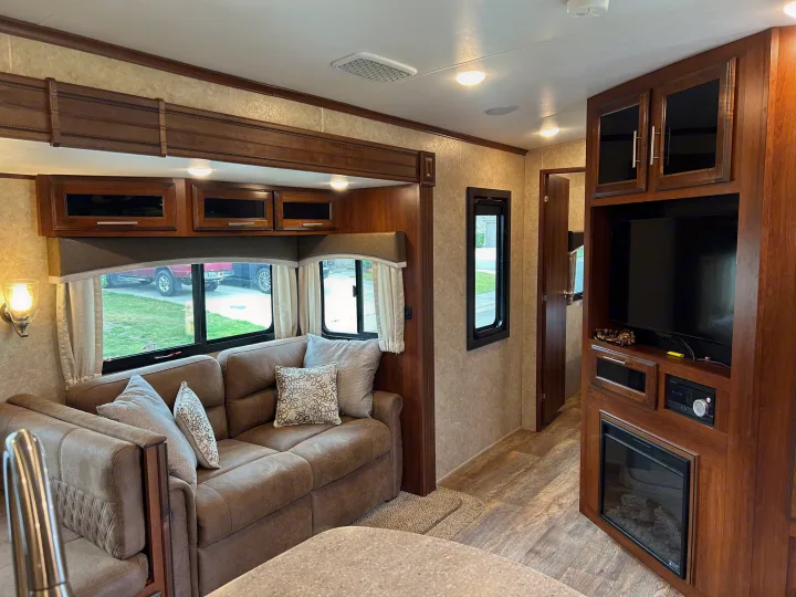 Spacious RV rental interior showcasing a comfortable living area with a sofa, entertainment center, and sleek kitchen countertop. Ideal for travel.. Jayco Eagle HT 2018