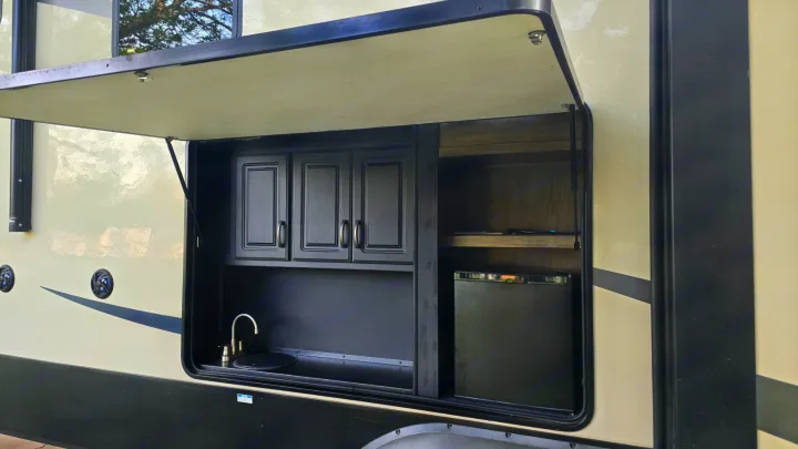 This RV rental offers a convenient outdoor kitchen with a sink, cabinets, and mini-fridge for enhanced camping.. Forest River Sandpiper 2021