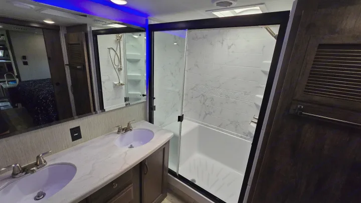 Modern RV rental bathroom: double vanity, spacious shower/tub combo, sleek design & amenities.. Forest River Sandpiper 2021