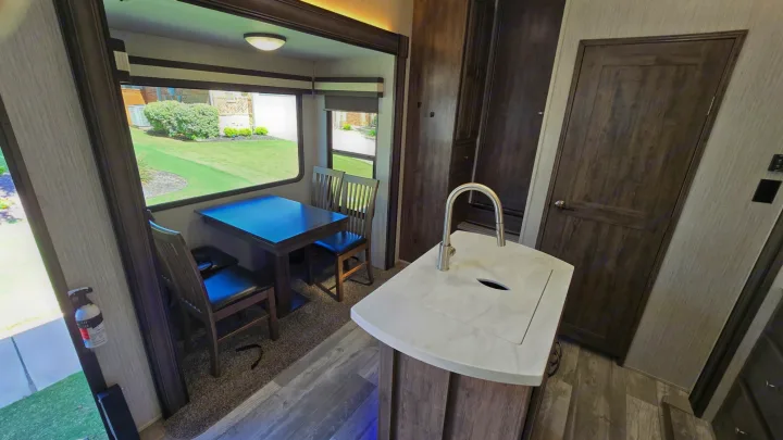 Spacious RV rental interior with a bright dining area featuring large windows, a modern kitchen island, and a sink.. Forest River Sandpiper 2021