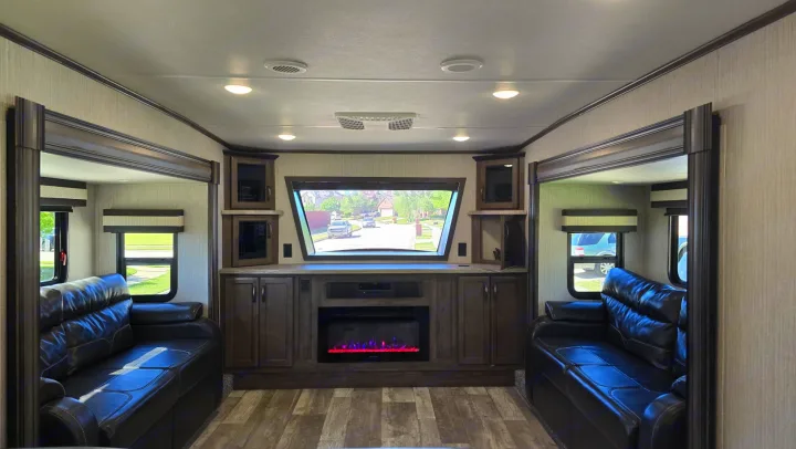 Spacious RV rental living area featuring dual sofas, a large window, entertainment unit, and electric fireplace.. Forest River Sandpiper 2021