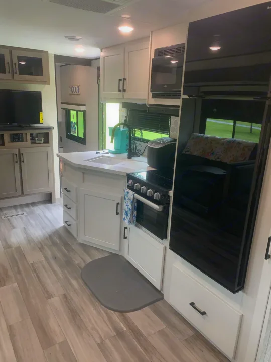 Modern RV rental interior, featuring a full kitchen with stove, fridge, microwave, and adjacent living space.. Jayco Jay Flight 324BDS 2024