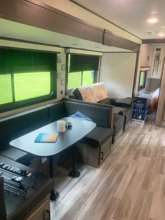 Modern RV rental interior featuring a dinette, comfortable lounge seating, and scenic window views of lush greenery.. Jayco Jay Flight 324BDS 2024