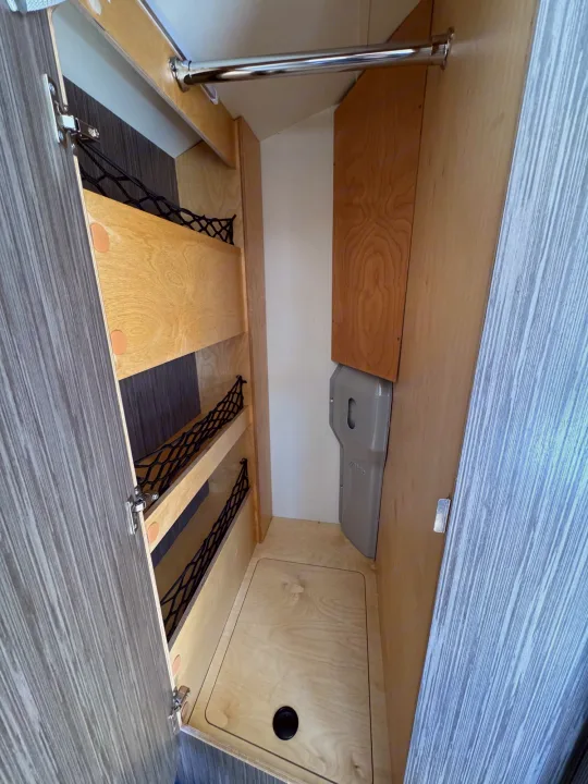 RV rental: Compact RV wardrobe/storage featuring a hanging bar, netting shelves, and a floor drain, designed for travel.. nuCamp T@B 2018