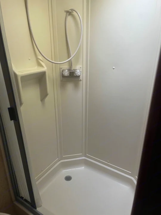 An RV rental shower: compact, clean, with a handheld showerhead, easy-to-use knobs, and built-in shelf.. Winnebago Other 2013