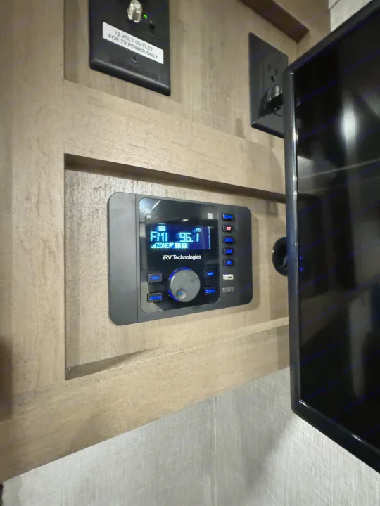 RV rental's iRV Technologies stereo showing 96.1 FM, with a 12V TV outlet for the mounted screen.. Jayco Jayflight 2024