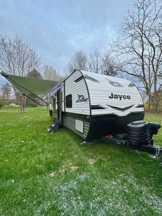 Our Jayco Jay Flight travel trailer RV rental, featuring an extended awning, parked on a lush green lawn.. Jayco Jayflight 2024