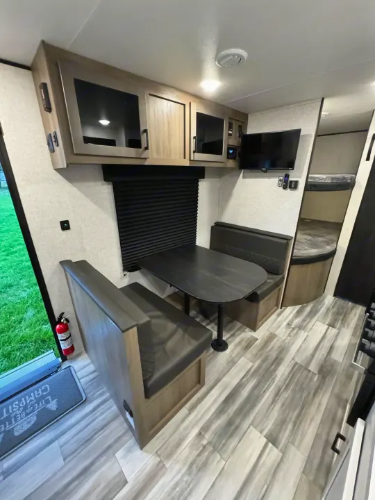 RV rental interior: dinette table with booth seating, overhead cabinets, and bunk beds visible for cozy travel.. Jayco Jayflight 2024