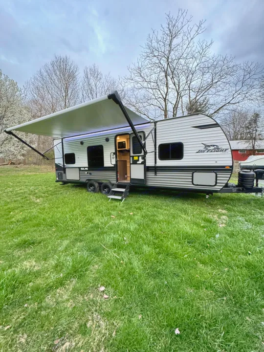 Spacious Jayco travel trailer with extended awning & steps on green grass. Perfect for an RV rental to explore the outdoors.. Jayco Jayflight 2024