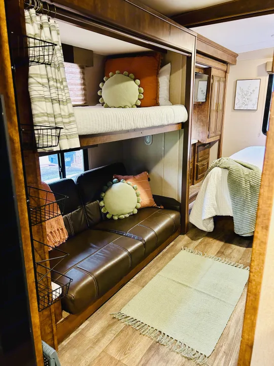 Cozy RV rental interior with a bunk bed, sofa, and main bed, featuring warm wooden tones and inviting decor.. FR3 FR3 Motorhome 2016