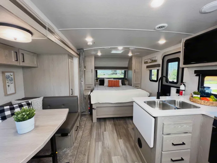 Bright rv rental interior, featuring a compact kitchen, dining area, and cozy bedroom with light wood accents.. Forest River Flagstaff Micro Lite 2022
