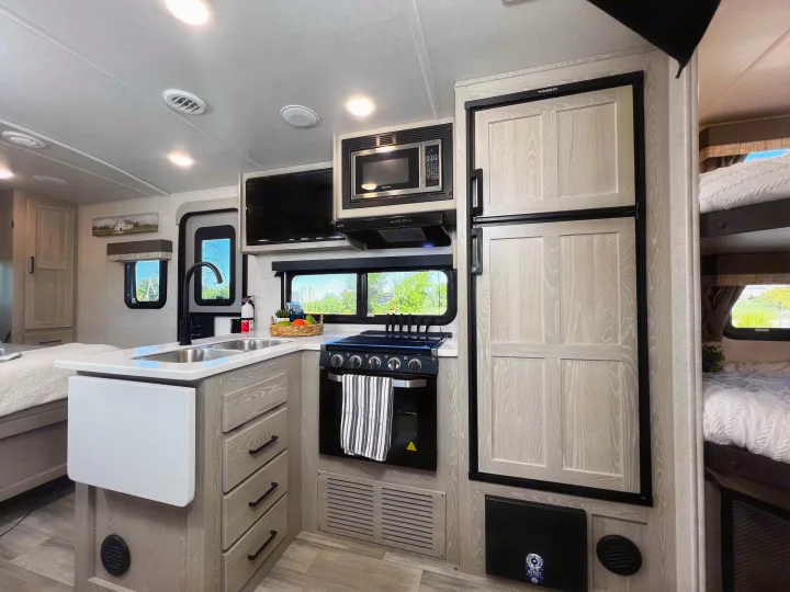 Stylish RV rental featuring a compact kitchen with sink, stove, microwave, and fridge, plus cozy sleeping areas.. Forest River Flagstaff Micro Lite 2022