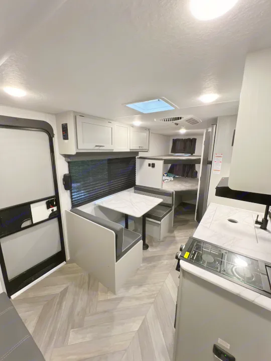 Explore this modern RV rental interior featuring a kitchenette, dinette, and bunk beds for comfortable travel.. Forest River Wildwood 2022