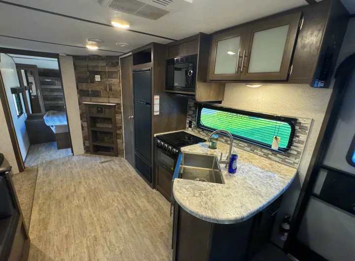 Modern RV rental interior: Full kitchen, fridge, microwave, and cozy bedroom. Perfect for your next adventure.. Aspen Trail Aspen Trail Trailer 2021