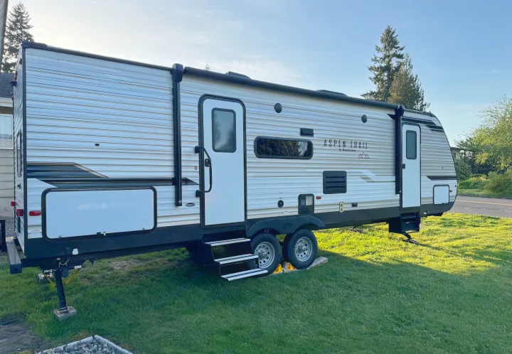 Aspen Trail travel trailer RV rental, parked on vibrant green grass, ready for your next outdoor adventure.. Aspen Trail Aspen Trail Trailer 2021
