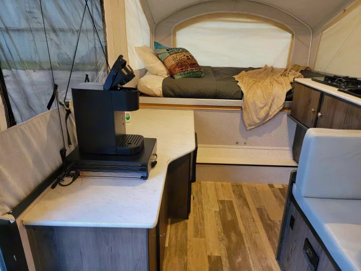 Cozy RV rental interior with a comfortable bed, functional kitchen counter, and coffee maker, ideal for camping.. Forest River Coachmen LS 2020