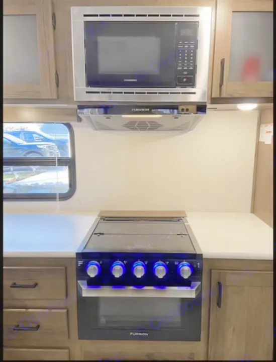 RV rental kitchen with stainless Furrion microwave, hood, and stove/oven. Blue lit knobs & ample counter space.. Forest River Tracer LE 2020