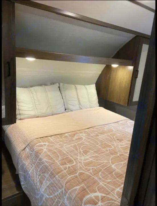 RV rental bedroom: A cozy bed with soft bedding, pillows, overhead storage, and reading lights for comfortable travels.. Forest River Tracer LE 2020