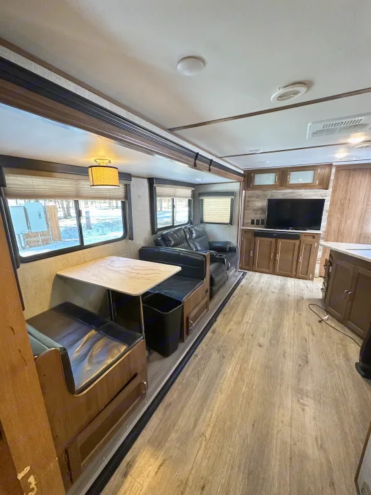 Spacious RV rental interior with a dinette, entertainment center, and recliners. Perfect for cozy travels!. Gulf Stream Envision 2020