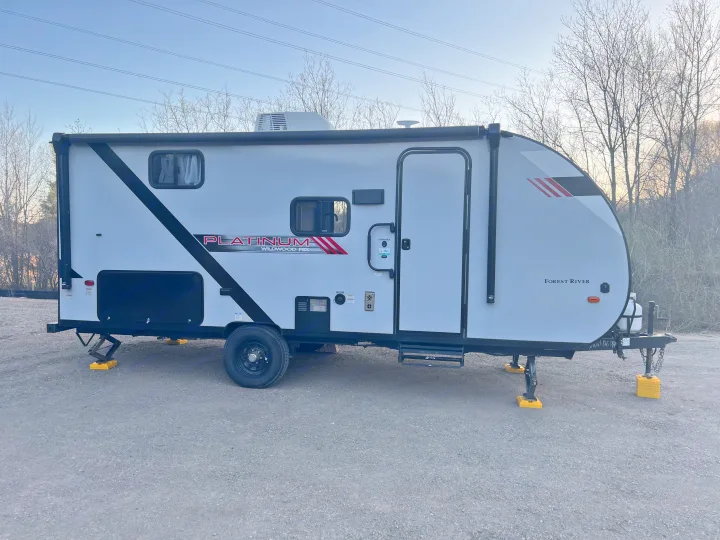 This parked Forest River Platinum Wildwood FSX travel trailer is ready for your next RV rental adventure, shown with leveling blocks.. Wildwood FSX 2021
