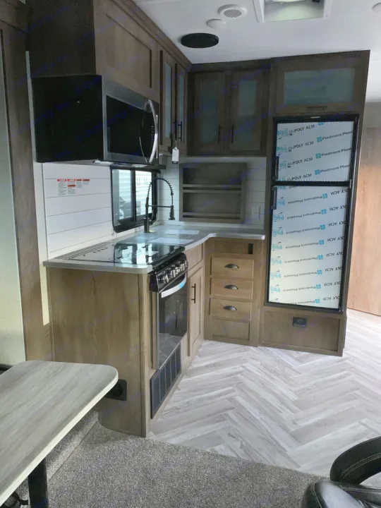 Clean, modern RV kitchen interior, ideal for your next rv rental. Features microwave, stove, sink, and herringbone flooring.. Forest River Stealth 2021