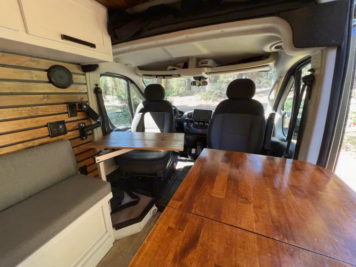 Spacious RV rental interior: wood-paneled walls, dining tables, comfy bench, and front cabin view.. Dodge Sprinter Van 2019