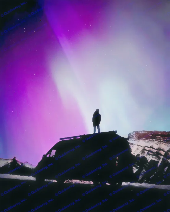 Unforgettable adventure: A person stands on an RV rental, witnessing the dazzling purple and teal Northern Lights overhead.. Dodge Sprinter Van 2019