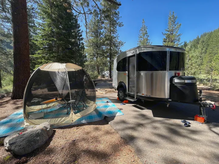 Perfect RV rental getaway! Airstream travel trailer with screen room set up at a peaceful forest campsite.. Airstream Basecamp 2022