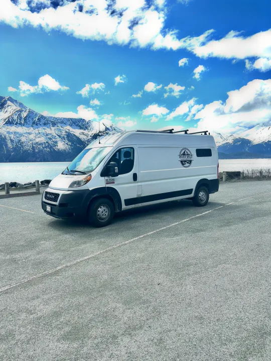 Scenic Alaska RV rental: white camper van by snow-capped mountains & calm water under blue skies.. Dodge Ram 2500 (Class B) 2021