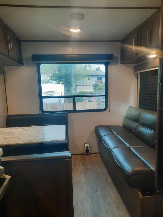 Inside an RV rental: a modern interior with a cozy dinette, comfortable sofa, and ample storage, ready for your next adventure.. Dutchmen Aspen 2020