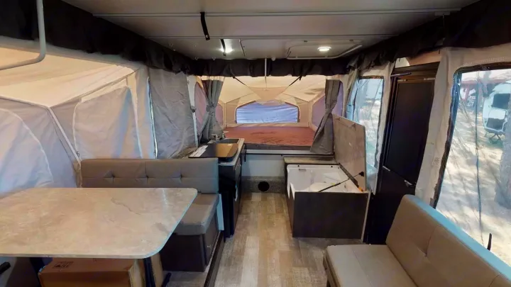 Spacious pop-up camper interior, ideal for RV rental adventures. Features dining, kitchen, and sleeping areas.. Forest River Rockwood ESP 2023