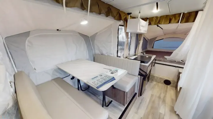 Spacious pop-up RV rental interior featuring a dinette, compact kitchen, and cozy tent beds for comfortable camping.. Forest River Rockwood ESP 2023