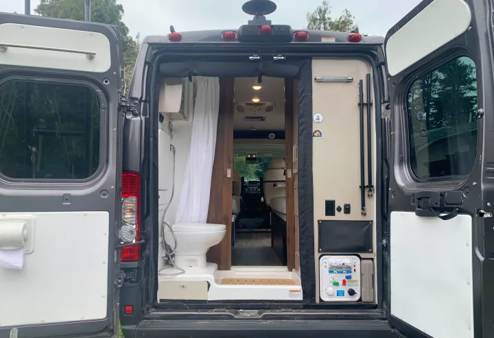 Inside an **rv rental**, the rear features a space-saving bathroom with a toilet, shower, and a visible utility panel.. Winnebago Travato 2022
