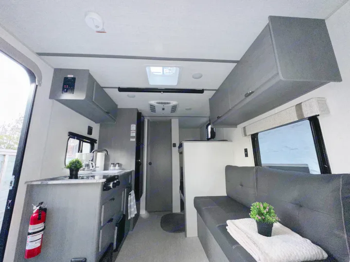 Experience comfort in this rv rental. View of a compact kitchen, cozy sofa, and overhead storage in a modern interior.. Forest River Ozark 2024
