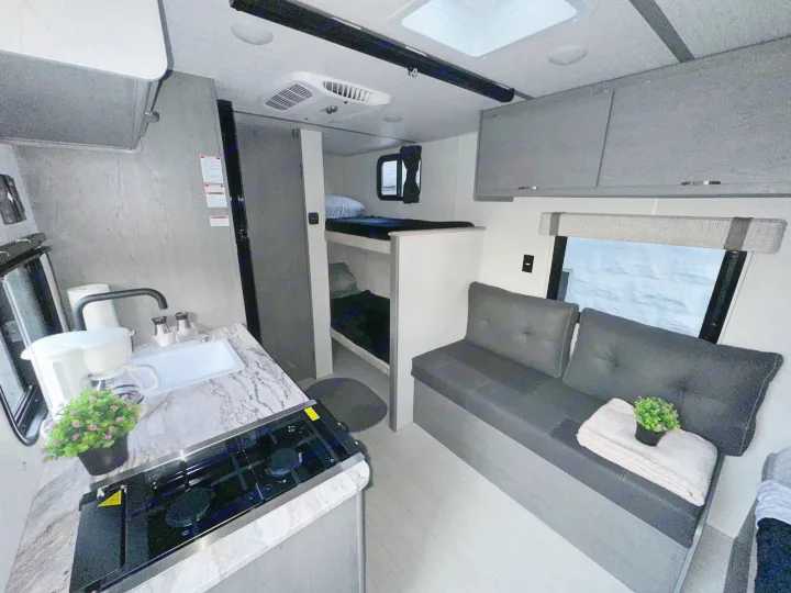 Compact RV rental interior featuring a full kitchen, cozy bunk beds, and a comfortable sofa for your next adventure.. Forest River Ozark 2024