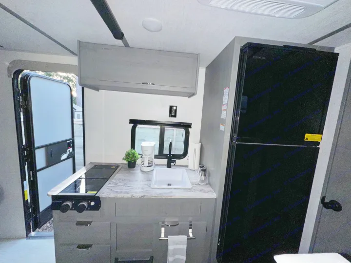 Well-equipped RV rental kitchen featuring a countertop, sink, stovetop, and refrigerator. Perfect for your mobile adventures.. Forest River Ozark 2024