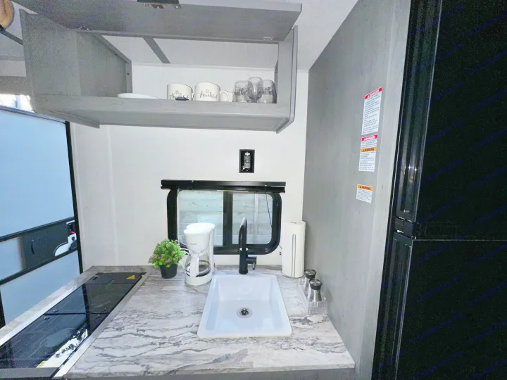 RV rental kitchen: bright interior with sink, stovetop, coffee maker, fridge, and overhead cabinets. Practical for trips.. Forest River Ozark 2024