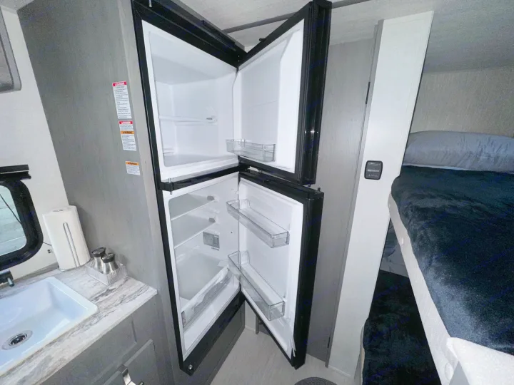 Inside an RV rental: features include a full-size fridge, kitchen sink, and comfortable bunk beds for travel.. Forest River Ozark 2024