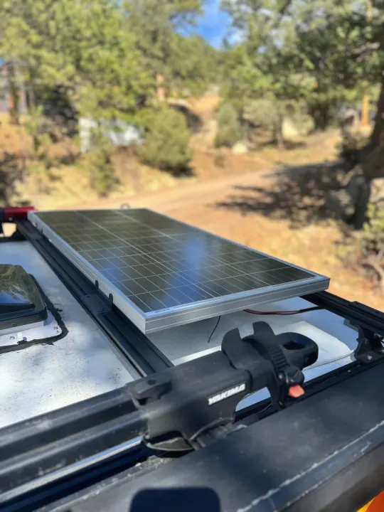 Close-up of a solar panel mounted on an RV rental's roof, providing green energy for outdoor exploration.. Custom Retro 2023