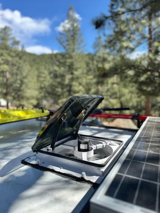 RV rental amenities: a rooftop fan and solar panel, with a kayak on the rack, ready for outdoor adventures.. Custom Retro 2023