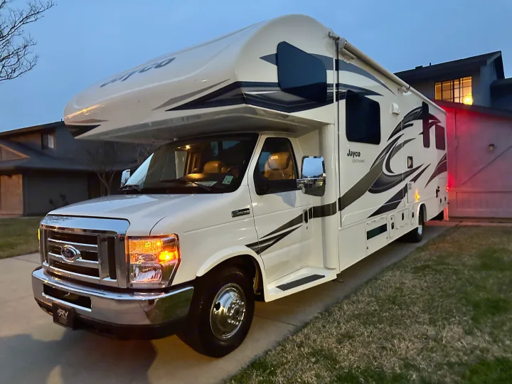 A pristine white Jayco Greyhawk Class C RV is parked on a paved driveway at dusk, ideal for an RV rental.. Jayco Greyhawk 2019