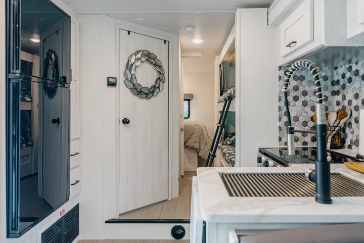 Modern RV rental interior with kitchen, bedroom, and bunk beds visible.. East to West Entrada 2024