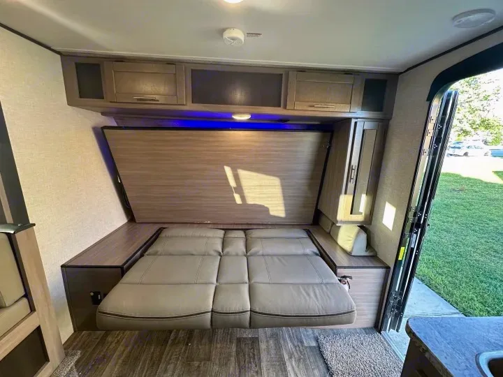 Inside this RV rental: a smart murphy bed setup with a convertible sofa, maximizing living space for your trip.. Crossroads Sunset Trail Super Lite 2022