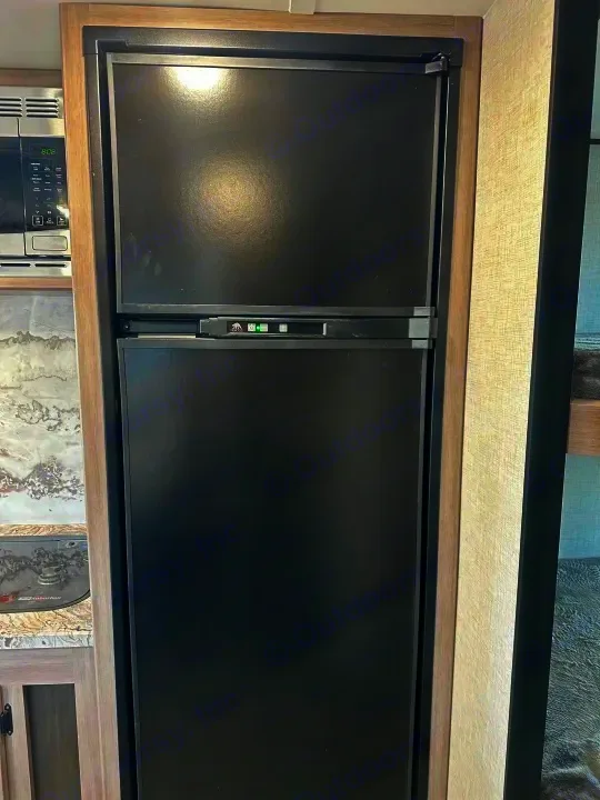 This RV rental features a sleek black refrigerator and freezer combo, perfect for keeping food cold.. Crossroads Sunset Trail Super Lite 2022