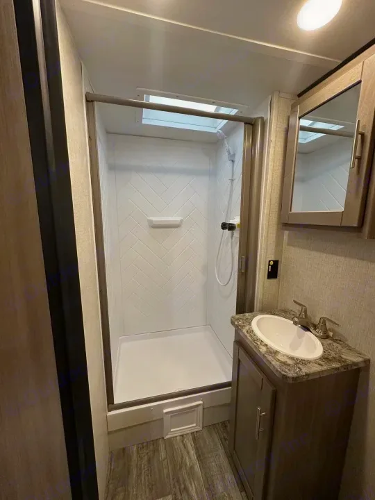 Inside an RV rental: a compact bathroom featuring a bright shower, vanity, and sink area.. Crossroads Sunset Trail Super Lite 2022
