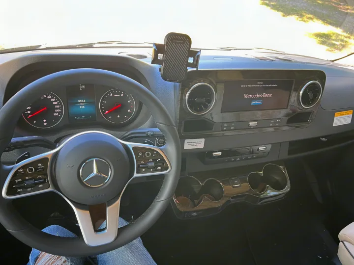 Mercedes-Benz RV rental interior: Driver's view of dashboard with steering wheel, digital display showing 858 miles.. Mercedes-Benz Sprinter 2024