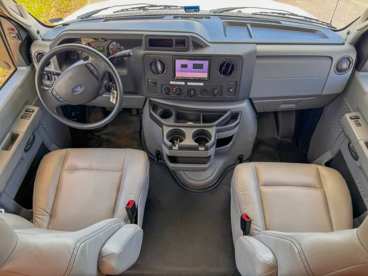 Ford RV rental front cabin showcasing light seats, steering wheel, and detailed dashboard controls.. Forest River Sunseeker 2021