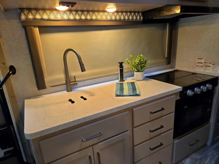 Bright rv rental kitchen: sleek sink, stove, microwave, pop-up outlet, and ample counter space for travel cooking.. Thor Quantum 2023